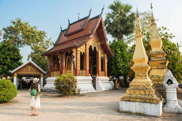 ผู้หญิงกำลังเดินบนทางเดินไม้ท่ามกลางทุ่งนาสีเขียวใกล้ประตูปาตูไซในเวียงจันทน์ ประเทศลาว ผู้หญิงกำลังเดินบนทางเดินไม้ท่ามกลางทุ่งนาสีเขียวใกล้ประตูปาตูไซในเวียงจันทน์ ประเทศลาว